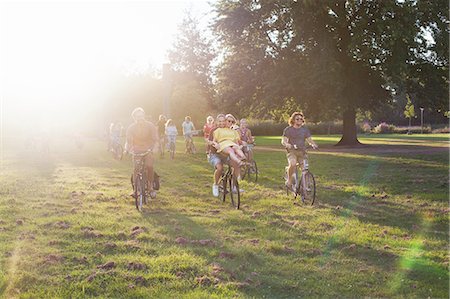 simsearch:649-08381087,k - Crowds of adult friends arriving on bicycles to sunset park party Foto de stock - Sin royalties Premium, Código: 649-08381113