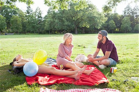 simsearch:649-08381087,k - Young man and woman chatting on picnic blanket at park party Foto de stock - Sin royalties Premium, Código: 649-08381137