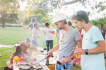 Young men barbecuing at group party in park Stock Photo - Premium Royalty-Free, Code: 649-08381180