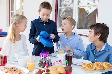 simsearch:649-07648247,k - Boy with siblings unwrapping birthday gifts on patio Stock Photo - Premium Royalty-Free, Code: 649-08381233