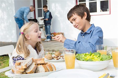 simsearch:649-07648247,k - Teenage boy feeding sister at garden barbecue table Stock Photo - Premium Royalty-Free, Code: 649-08381268