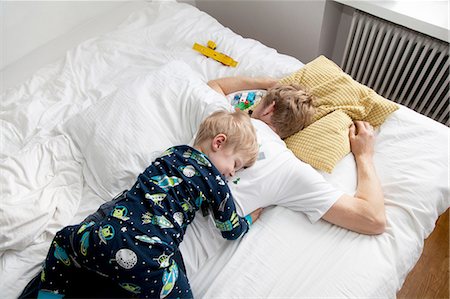 sleepy - Young boy lying on top of father n bed Stock Photo - Premium Royalty-Free, Code: 649-08381271