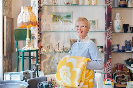 second hand - Portrait of mature woman folding yellow blanket in vintage shop Stock Photo - Premium Royalty-Free, Code: 649-08381297