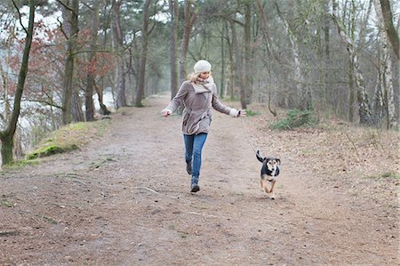 Mid adult woman running with her dog in forest Stock Photo - Premium Royalty-Free, Code: 649-08381684