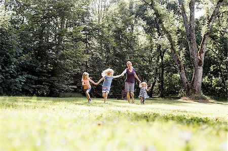 simsearch:649-07280282,k - Mid adult woman and three young daughters holding hands and running in park Stock Photo - Premium Royalty-Free, Code: 649-08422516