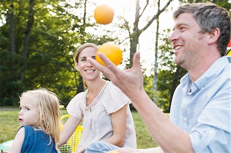 simsearch:649-08422552,k - Mature man juggling oranges at family picnic in park Foto de stock - Sin royalties Premium, Código: 649-08422536