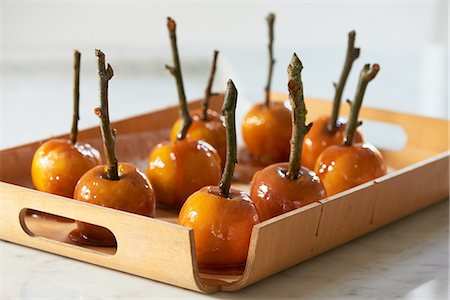 Toffee apples on sticks hardening on wooden tray Stock Photo - Premium Royalty-Free, Code: 649-08423038
