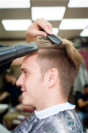 Side view of young man in barbershop having hair blow dried Stock Photo - Premium Royalty-Free, Code: 649-08479646
