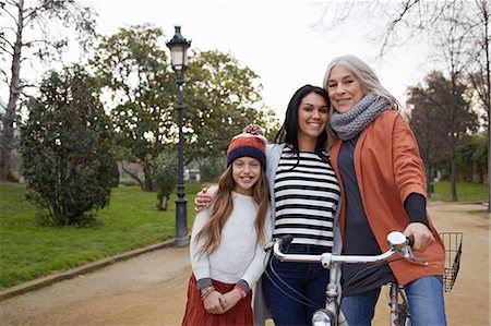 family on bicycle in park - Mother and daughter and grandmother in park with bicycle looking at camera smiling Stock Photo - Premium Royalty-Free, Code: 649-08544317