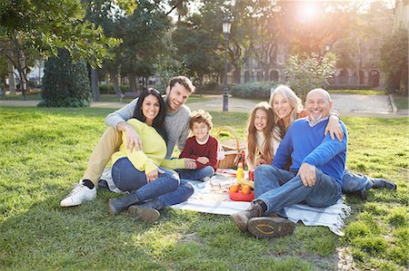 Multi generation family sitting on grass having picnic, looking at camera smiling Stock Photo - Premium Royalty-Free, Code: 649-08544336