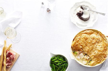 Overhead view of dinner table with chicken and leek pie, green beans and chocolate pudding dessert Stock Photo - Premium Royalty-Free, Code: 649-08548201