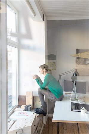 simsearch:649-07119200,k - View through glass, full length side view of mature woman sitting on desk looking out of window Stock Photo - Premium Royalty-Free, Code: 649-08548454