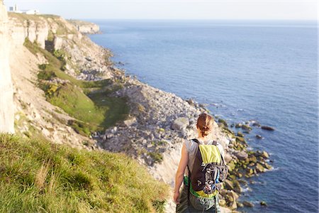 simsearch:649-08086253,k - Rear view of woman with backpack looking at view of ocean, Portland, UK Stock Photo - Premium Royalty-Free, Code: 649-08548852