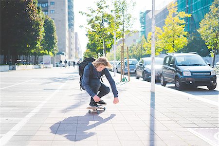 simsearch:649-07710443,k - Young male skateboarder crouching whilst skateboarding on sidewalk Stock Photo - Premium Royalty-Free, Code: 649-08548896