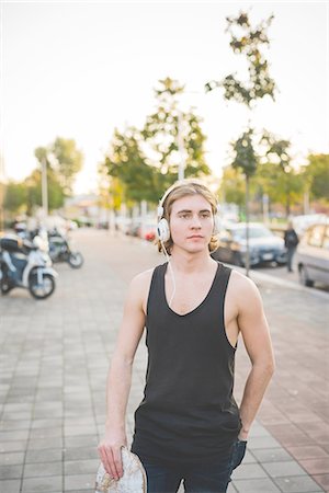 simsearch:649-07710443,k - Portrait of young male urban skateboarder listening to headphone music on sidewalk Stock Photo - Premium Royalty-Free, Code: 649-08548927