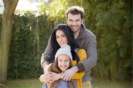 simsearch:693-06013834,k - Parents standing behind daughter, arms around, looking at camera smiling Stock Photo - Premium Royalty-Free, Code: 649-08548960