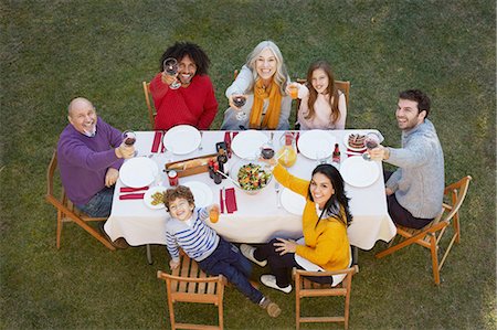 senior folding chair - Overhead view of multi generation family dining outdoors looking up at camera, making a toast smiling Stock Photo - Premium Royalty-Free, Code: 649-08548974