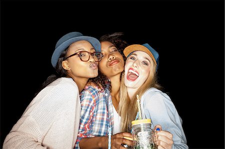 Young women huddled together holding mason jars looking at camera puckering lips Stock Photo - Premium Royalty-Free, Code: 649-08542996