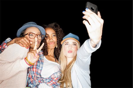 simsearch:614-06973867,k - Young women huddled together making peace sign, puckering lips, using smartphone to take selfie Photographie de stock - Premium Libres de Droits, Code: 649-08542998