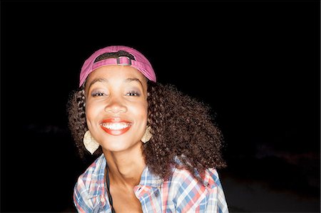 simsearch:649-07560393,k - Portrait of young woman wearing baseball cap backwards looking at camera smiling Photographie de stock - Premium Libres de Droits, Code: 649-08543002