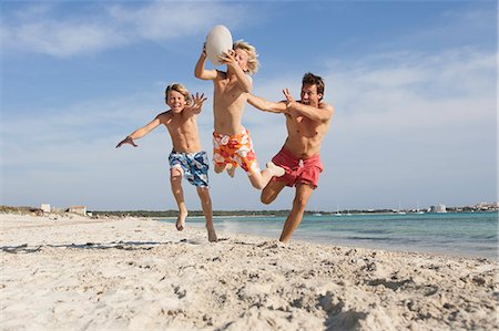 simsearch:649-07648247,k - Boy jumping with rugby ball chased by brother and father on beach, Majorca, Spain Stock Photo - Premium Royalty-Free, Code: 649-08543614