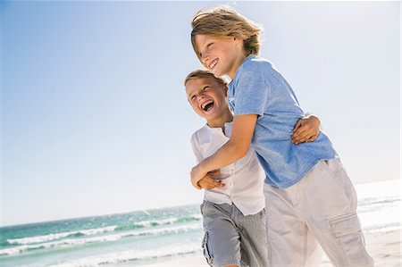 Brothers on beach hugging looking away smiling Photographie de stock - Premium Libres de Droits, Code: 649-08543776