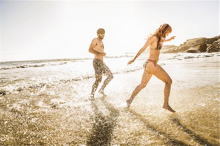 simsearch:649-07585546,k - Mid adult couple wearing bikini and swimming shorts splashing in sea, Cape Town, South Africa Stock Photo - Premium Royalty-Free, Code: 649-08543988