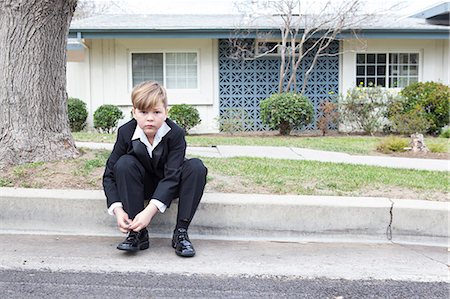 Boy in suit sitting on suburban street Photographie de stock - Premium Libres de Droits, Code: 649-08561842