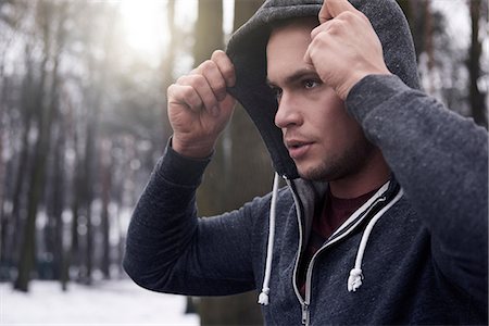 Young man wearing hooded sweatshirt, in snowy, rural landscape Stock Photo - Premium Royalty-Free, Code: 649-08576257