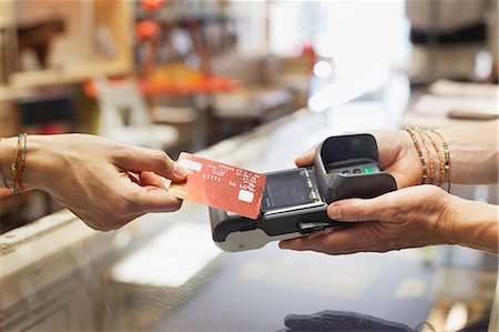 people holding cards in hand - Cropped view of womens hand using credit card to make contactless payment on chip and pin machine Stock Photo - Premium Royalty-Free, Code: 649-08576898
