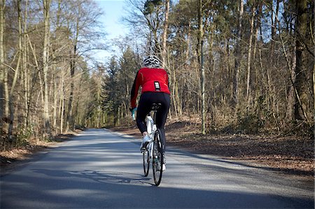 simsearch:649-08900720,k - Rear view of woman cycling on tree lined road Stock Photo - Premium Royalty-Free, Code: 649-08576916