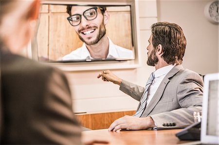 skype - Over the shoulder view of business people in boardroom having video call meeting Stock Photo - Premium Royalty-Free, Code: 649-08576952