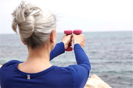 Mature woman beside sea, exercising with hand weights, rear view Stock Photo - Premium Royalty-Free, Code: 649-08577020