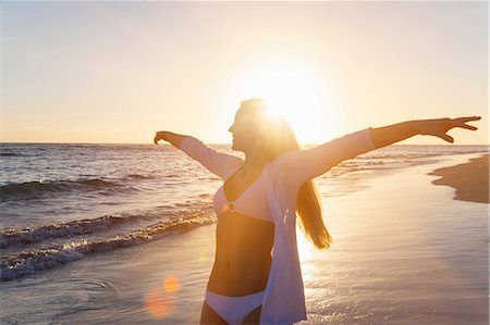 Young woman dancing with arms open on beach at sunset, Dominican Republic, The Caribbean Stock Photo - Premium Royalty-Free, Code: 649-08577298