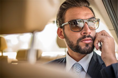 Young businessman wearing sunglasses talking on smartphone in car  backseat, Dubai, United Arab Emirates Foto de stock - Sin royalties Premium, Código: 649-08577513