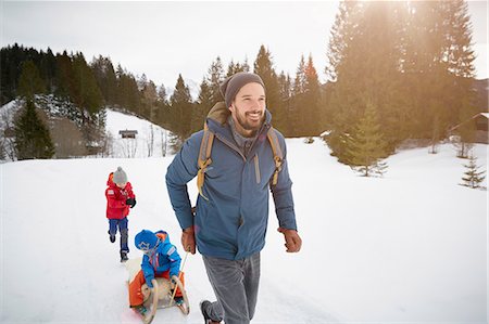 Young man pulling sons on toboggan in snow covered landscape, Elmau, Bavaria, Germany Stock Photo - Premium Royalty-Free, Code: 649-08577730