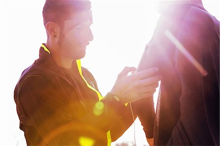 Mid adult man adjusting friends activity tracker Stock Photo - Premium Royalty-Free, Code: 649-08660558