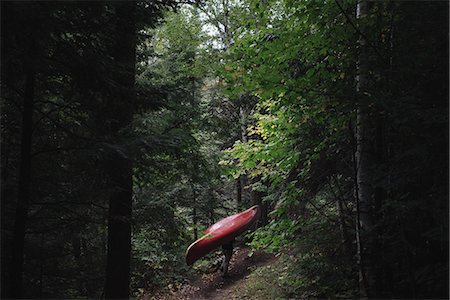 Mid adult woman carrying canoe through forest Stock Photo - Premium Royalty-Free, Code: 649-08660591