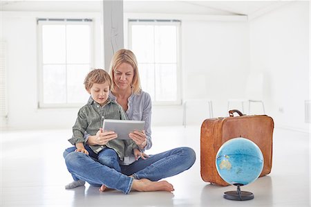 family suitcases - Mature woman and son sitting on floor looking at digital tablet Stock Photo - Premium Royalty-Free, Code: 649-08661045