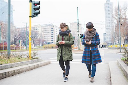 Two sisters walking along street, using smartphones Stock Photo - Premium Royalty-Free, Code: 649-08661803