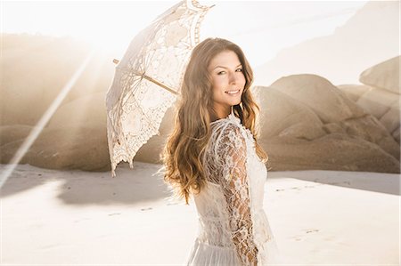 smiling one person - Portrait of beautiful woman holding parasol looking over her shoulder on sunlit beach, Cape Town, South Africa Stock Photo - Premium Royalty-Free, Code: 649-08661920