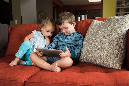 Siblings using digital tablet on sofa Stock Photo - Premium Royalty-Free, Code: 649-08702098