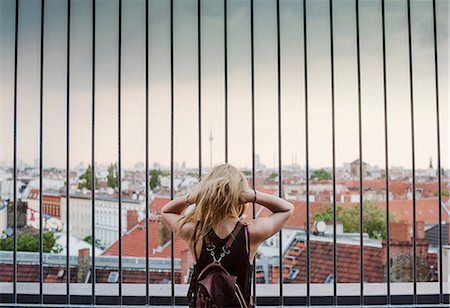 Young woman looking through railings, at view across rooftops, rear view Stock Photo - Premium Royalty-Free, Code: 649-08702267