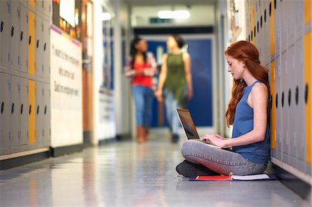simsearch:614-07031973,k - Young female college student sitting on locker room floor typing on laptop Stock Photo - Premium Royalty-Free, Code: 649-08702358