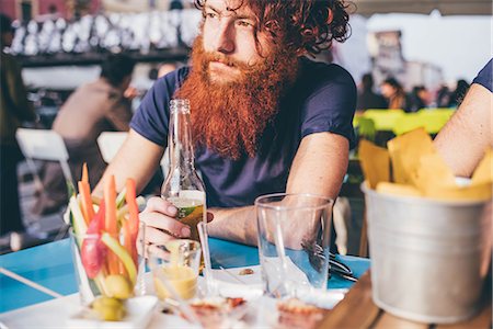 simsearch:649-08702620,k - Young male hipster with red hair and beard drinking bottled beer at sidewalk bar Stock Photo - Premium Royalty-Free, Code: 649-08702654