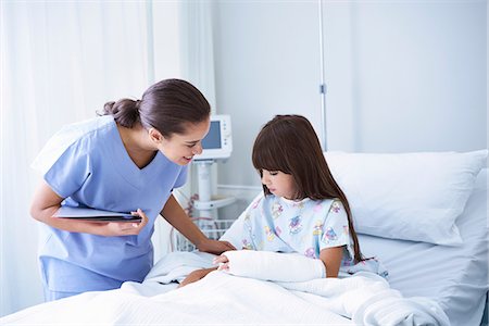 Female nurse explaining to girl patient with arm plaster cast in hospital children's ward Stock Photo - Premium Royalty-Free, Code: 649-08702719