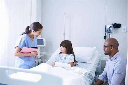 Female nurse explaining to girl patient with arm plaster cast in hospital children's ward with father Stock Photo - Premium Royalty-Free, Code: 649-08702720