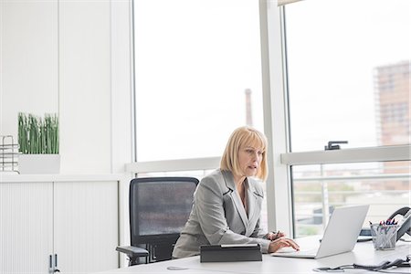 Mature businesswoman reading update on office laptop Stock Photo - Premium Royalty-Free, Code: 649-08702835