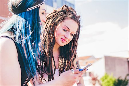 Two young women reading smartphone texts in urban housing estate Stock Photo - Premium Royalty-Free, Code: 649-08703297