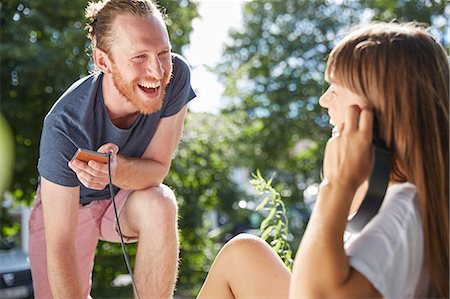 Young couple outdoors, listening to music through earphones Stock Photo - Premium Royalty-Free, Code: 649-08714351